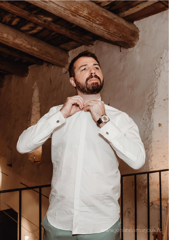 Homme en chemise blanche fermant son col, les poignets en manchettes mousquetaires fermées par des boutons de manchette