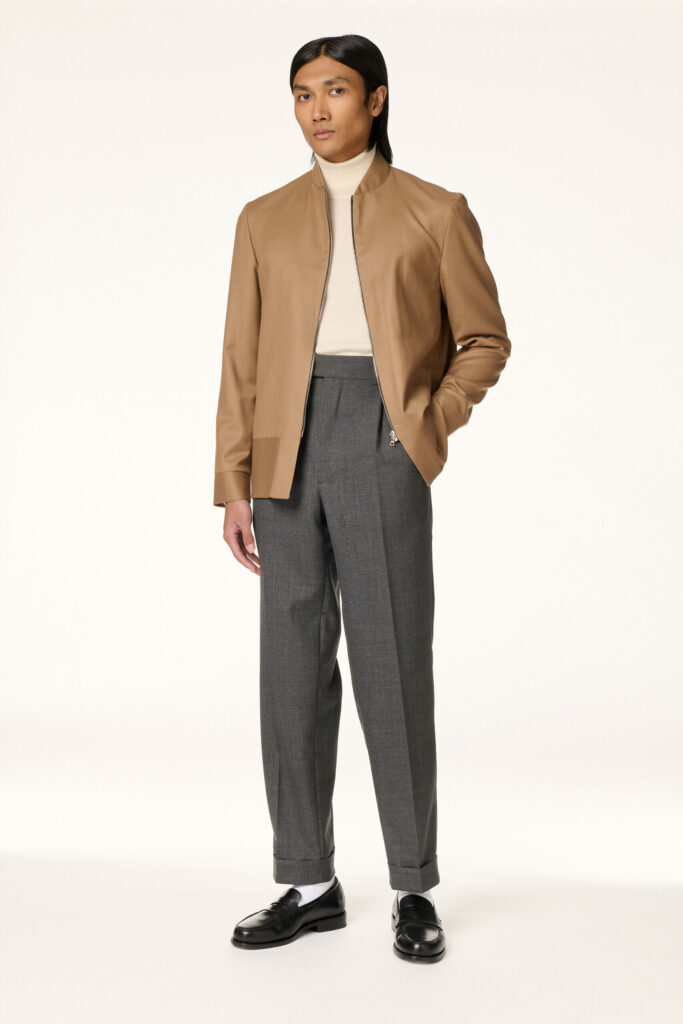 Pantalon gris à pinces et revers porté avec un col roulé écru et un blouson camel, RIVES Paris
